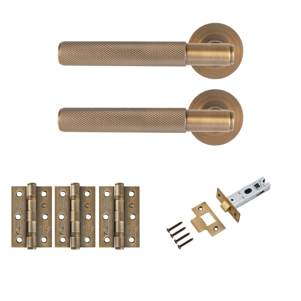 Antique brass knurled lever door handle set with round rose backplates, three matching brass door hinges, tubular latch, strike plate and fixing screws for internal doors.